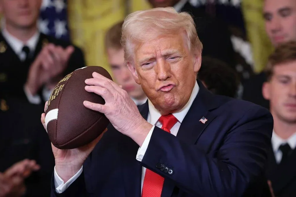 President Donald Trump holds up a football presented to him during a presentation ceremony for the Commander-in-Chief Trophy.