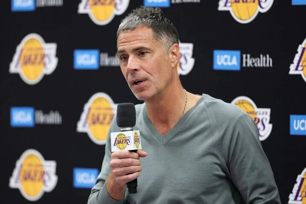 Lakers president of basketball operations and general manager Rob Pelinka speaks while holding a Lakers microphone.